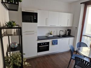 Una cocina con gabinetes blancos y un fregadero y una mesa. en Beki's apartment, en Alba