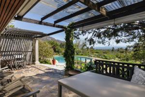 a patio with a table and a view of a pool at Watermill Studios in Gordonʼs Bay