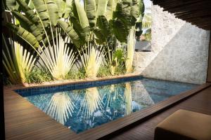 a pool in a house with a palm tree at Casa com Ofurô, Piscina Aquecida e Cozinheira in Barra do Camaragibe