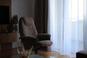 a chair sitting in a living room next to a window at Stan na dan Luna in Smederevska Palanka
