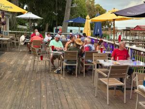 eine Gruppe von Personen, die an Tischen in einem Restaurant im Freien sitzen in der Unterkunft Porky's Lodge, Bar & Grill in Georgetown