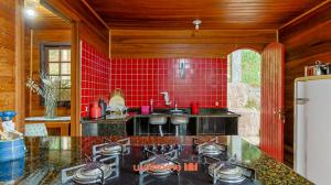 a kitchen with a stove and a red tile wall at Casa em Mangaratiba com 3 suites e Vista Mar in Mangaratiba