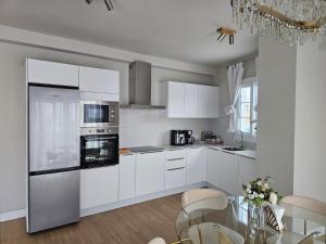 a kitchen with white cabinets and a glass table at Ático Monarca II in Arrecife