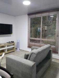 a living room with a couch and a flat screen tv at Encantador refugio enclavado en las montañas in Guadual