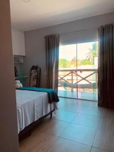 a bedroom with a bed and a view of a balcony at Portuá Chalés in São Miguel dos Milagres