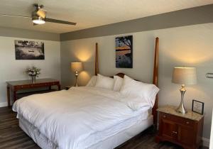 1 Schlafzimmer mit einem großen weißen Bett und 2 Tischen in der Unterkunft Porky's Lodge, Bar & Grill in Georgetown