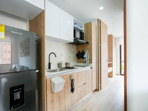 a kitchen with white cabinets and a refrigerator at High Park 94 by Jalo in Bogotá