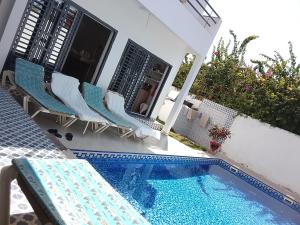 a swimming pool with chairs next to a house at keur Baye fall fall saly in Sali Nianiaral