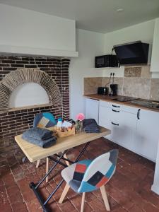 eine Küche mit einem Tisch, Stühlen und einem Backsteinofen in der Unterkunft Maisonnette au calme 