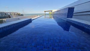 a swimming pool with blue tiles on the side of a building at Frente Mar Bessa João Pessoa in João Pessoa
