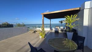 a patio with a table and chairs and the ocean at Frente Mar Bessa João Pessoa in João Pessoa