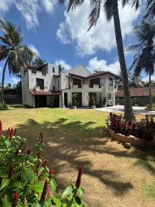 a large white house with palm trees and a yard at PereraTree in Ja-Ela