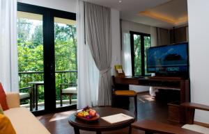 a living room with a television and a table with a keyboard at Tanjung Rhu Resort in Tanjung Rhu