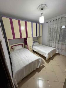 a bedroom with two beds and a striped headboard at Crystal Heart Fier in Fier