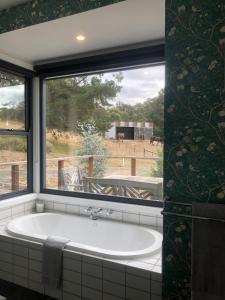 eine Badewanne im Bad mit Fenster in der Unterkunft The FatPonyLodge in Hepburn Springs