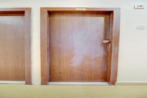 two wooden doors in a room with a wall at Hotel O Della Comforts in Ambernath