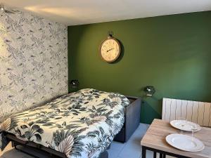 a bedroom with a bed and a clock on the wall at Les Orchidées 1 in Le Tréport