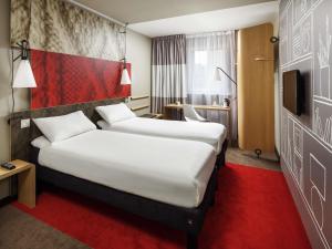 a hotel room with two beds and a tv at ibis Glasgow City Centre – Sauchiehall St in Glasgow