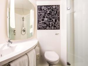 a bathroom with a toilet and a sink and a mirror at ibis London Wembley in London +56 photos