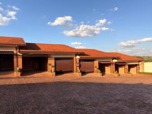 a building with brown roofs and a brick driveway at Status Motel Ourinhos in Ourinhos