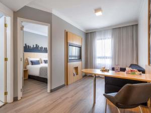 a hotel room with a bed and a desk with a desk at Mercure Sao Paulo Pinheiros in Sao Paulo