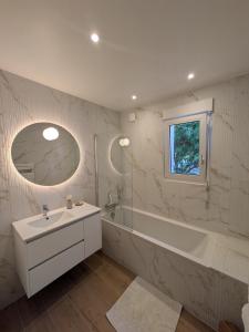 a white bathroom with a tub and a sink and a bath tubermott at La p'tite marquise in Roscoff