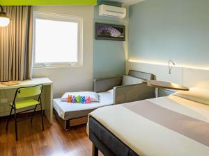 a room with two beds and a desk and a chair at ibis Styles Curitiba Centro Civico in Curitiba