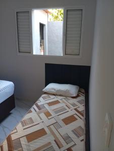 ein Schlafzimmer mit einem Bett und zwei Fenstern. in der Unterkunft Recanto Amora in Boicucanga