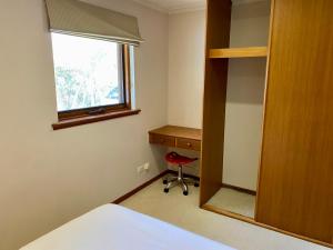 a bedroom with a bed and a desk and a window at Hillside Retreat With Pool in Flagstaff Hill