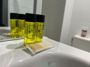 Tres botellas amarillas sobre un lavabo en un baño en COMM - Proudhon 6 - SC - Séjour moderne à Besançon, en Besançon