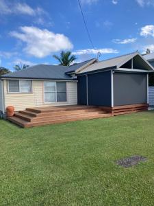 a house with a wooden deck in a yard at Riverview Cottage in Dunbogan
