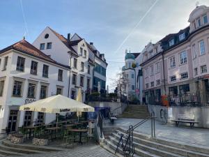 a street with an umbrella and tables and buildings at Allgäu-Nest mit Stellplatz in Durach