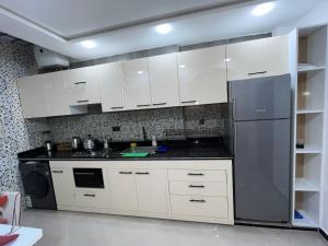a kitchen with white cabinets and a stainless steel refrigerator at Appart de Luxe à LAVERDA - à 400m de la plage in Dakhla