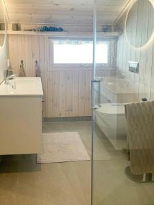 ein Badezimmer mit Dusche, Badewanne und Waschbecken in der Unterkunft Cabin With Views In Langsua National Park in Heggenes