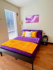 een slaapkamer met een bed met paarse en oranje lakens bij Purple Palace - Downtown STL Studio in Saint Louis