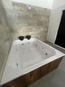 een groot wit bad met twee zwarte kommen erbovenop bij La Gruta Glamping in Fúquene