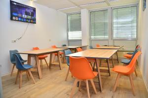 ドライアイヒにあるXenon hostelsの木製のテーブルとオレンジ色の椅子のある教室