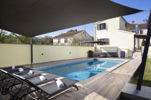 a swimming pool with a table and an umbrella at Ferienhaus Captains in Vintijan