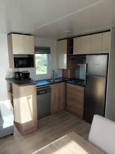 a kitchen with wooden cabinets and stainless steel appliances at Val'B ocean-bord de plage in Sarzeau