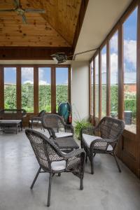 eine abgeschirmte Veranda mit Stühlen, Tischen und Fenstern in der Unterkunft Lancefield Guest House in Lance Field