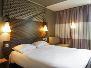 a hotel room with a large bed and a chair at ibis Paris La Defense Courbevoie in Courbevoie