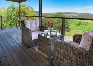 eine Veranda mit Korbstühlen und einem Tisch mit Aussicht in der Unterkunft Grasmere Farm in Gruyere