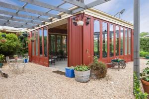 a red house with glass doors and a patio at Lancefield Guest House in Lance Field