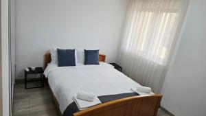 a bedroom with a bed with blue pillows and a window at Apartman Car in Novi Pazar