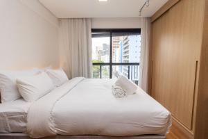 a bedroom with a large white bed with a window at Studios Sampa - Vila Buarque - Santa Casa in São Paulo