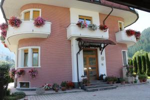 a pink house with potted plants and flowers at Villa Alessandra in Colle Isarco