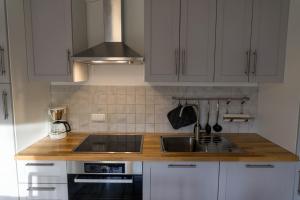 Una cocina con gabinetes blancos, un fregadero y una estufa. en Aurora Lodge, en Frielendorf 4 fotos más