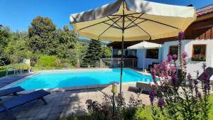 a pool with an umbrella next to a house at Ferienwohnung In Bayerisch Eisenstein Mit Garten in Bayerisch Eisenstein