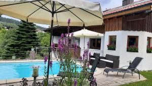 a house with an umbrella and a swimming pool at Ferienwohnung In Bayerisch Eisenstein Mit Garten in Bayerisch Eisenstein