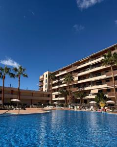 a large swimming pool in front of a hotel at Türkiz Kánaán Apartman in Puerto de Santiago